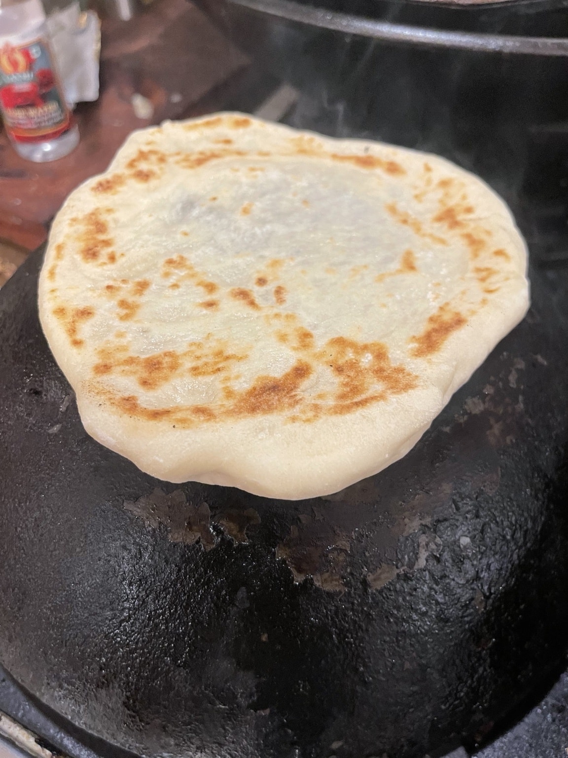 Lavash cooking on an inverted wok over an open flame